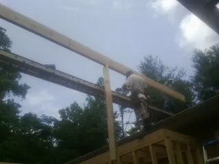 Carpenter setting a ridge beam over a new addition frame — Ice Dam Removal by Roofing Brothers in Hanson