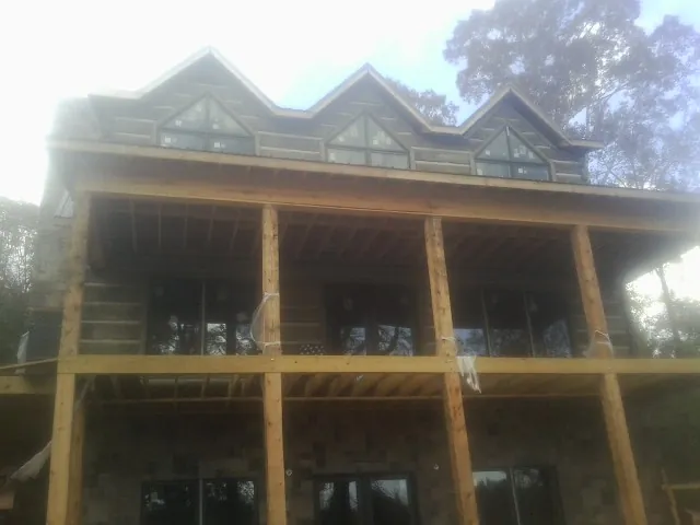 Dormers and porch framing on a large log home under construction — Roof Coating work by our crew in Hanson