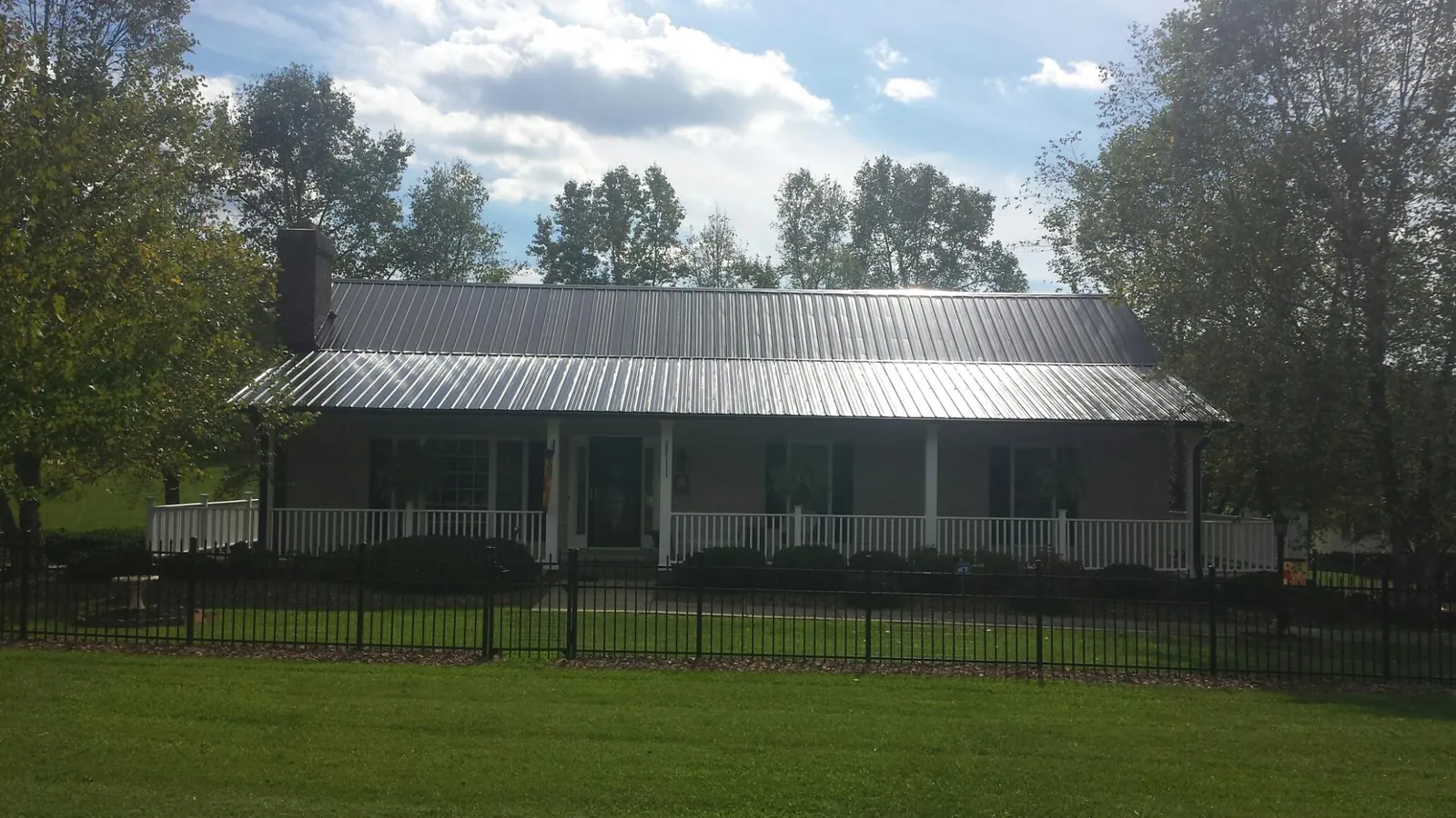 Gray metal roof on a brick ranch with a full width front porch — Gutter Guard Installation work by our crew in Hanson