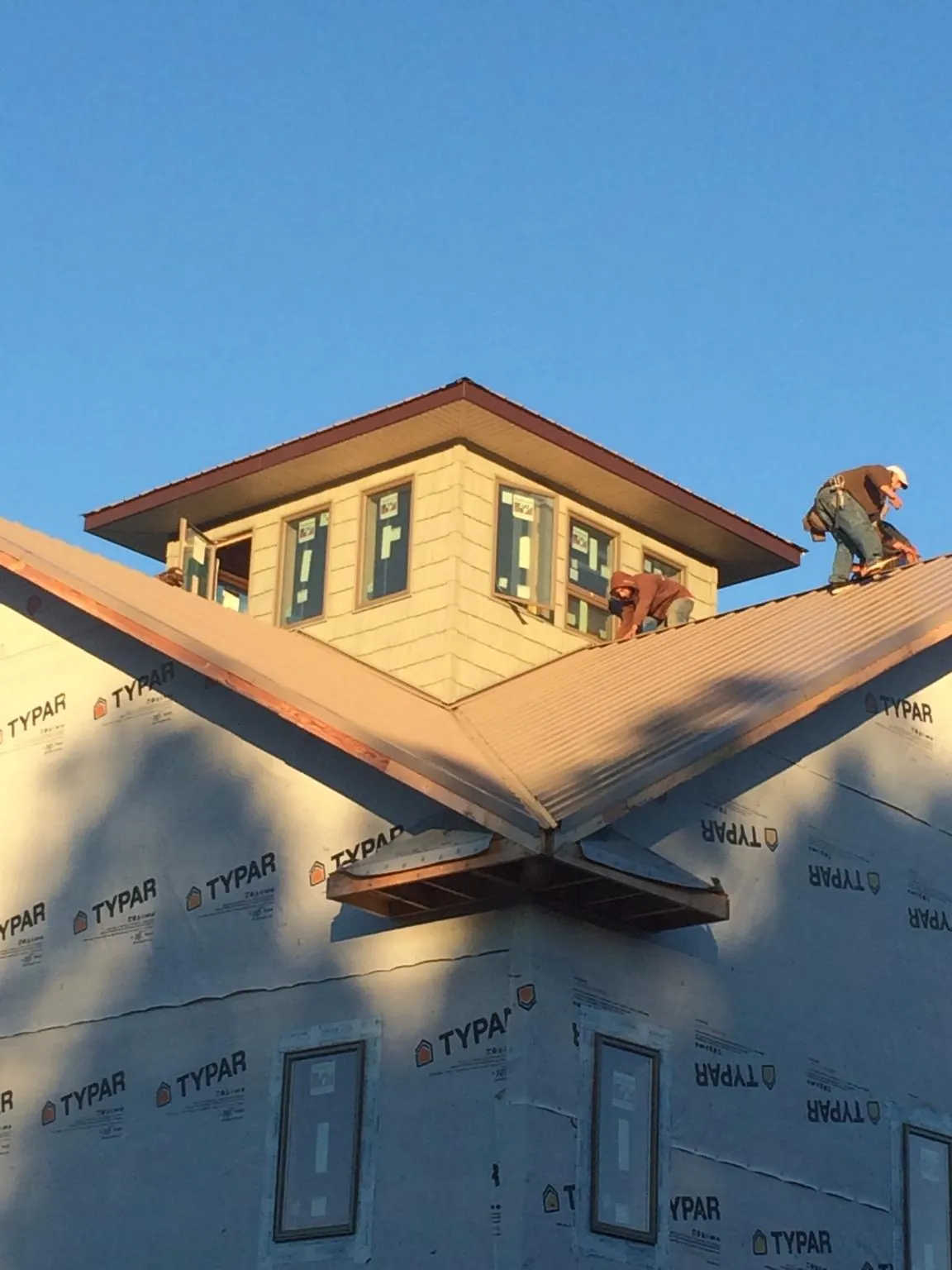 Roofers working around a rooftop cupola on a new metal roof at sunset — Roof Waterproofing in Hanson by Roofing Brothers